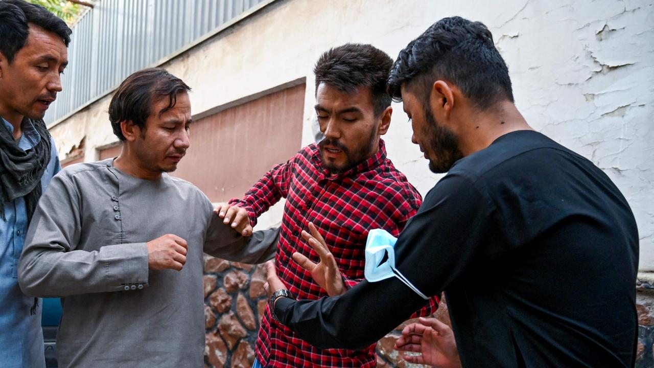 Journalist Nematullah Naqdi (centre) is helped by his colleagues as he arrives at their office after being released from Taliban custody in Kabul. Picture: Wakil Kohsar/AFP