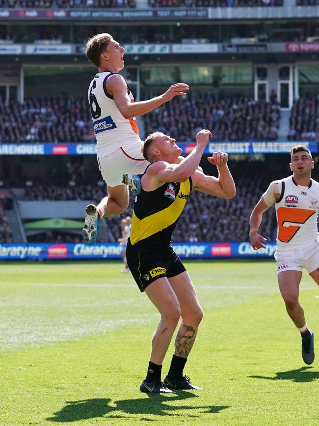 Lachie Whitfield of the Giants flies high over Josh Caddy. Picture: AAP