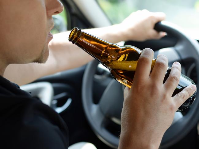 The concept of alcohol driving crime - closeup of young male driver hands with steering wheel and bottle of beer. Drink driving generic. Picture: iSTOCK