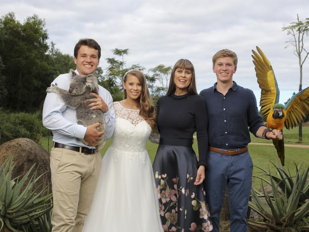 Chandler Powell, Bindi Irwin, Terri Irwin and Robert Irwin in a family photo. Chandler Powell is holding a koala and Robert Irwin is holding a macaw.