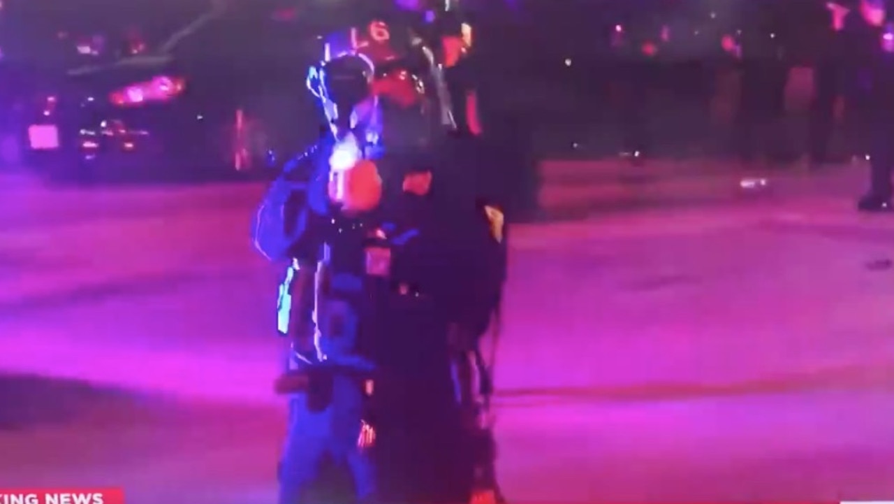 A police officer points his weapon directly at the camera.