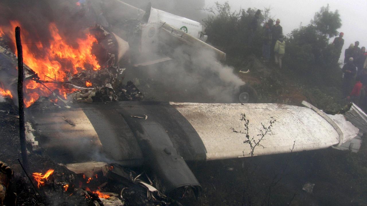 Bystanders look on as the wreckage of a Yeti Airlines aircraft burns at Lukla Airport in 2008.