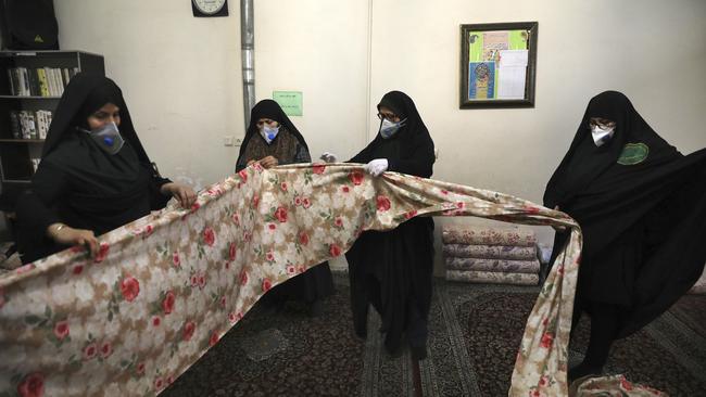 Volunteer women wearing face masks sew bedsheets for hospitals in a mosque in southern Tehran, Iran. Picture: AP