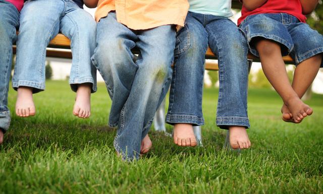 Dirty Legs and Feet of Children Sitting on a Bench