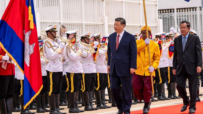 Xi Jinping with Cambodia's Senate President Hun Sen (R) walks past an honour guard at Phnom Penh International Airport. Picture: AFP.