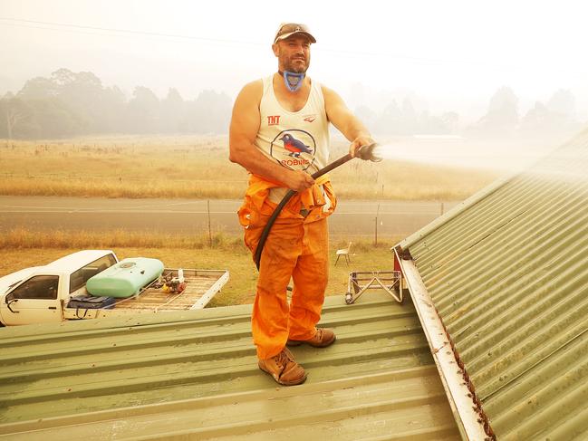 David “Chunky” Reynolds defends his home by sparying down his roof at Arve Road, Geeveston. Picture: RICHARD JUPE