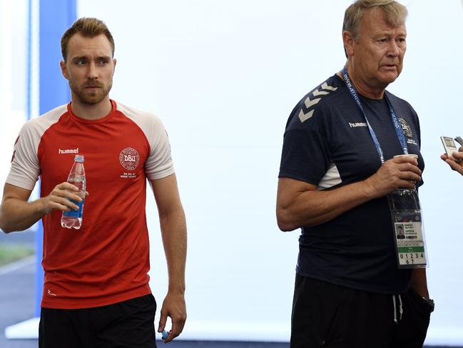 Denmark's midfielder Christian Eriksen (L) walks past Denmark's head coach Age Hareide (R) speaking to the press after a training session of Denmark's national football team on June 12, 2018, in Vityazevo ahead of the Russia 2018 World Cup football tournament.  / AFP PHOTO / Jonathan NACKSTRAND