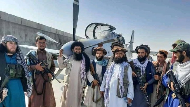 Taliban fighters beside an abandoned Afghani military plane at the Mazar-e Sharif air base. Picture: Twitter