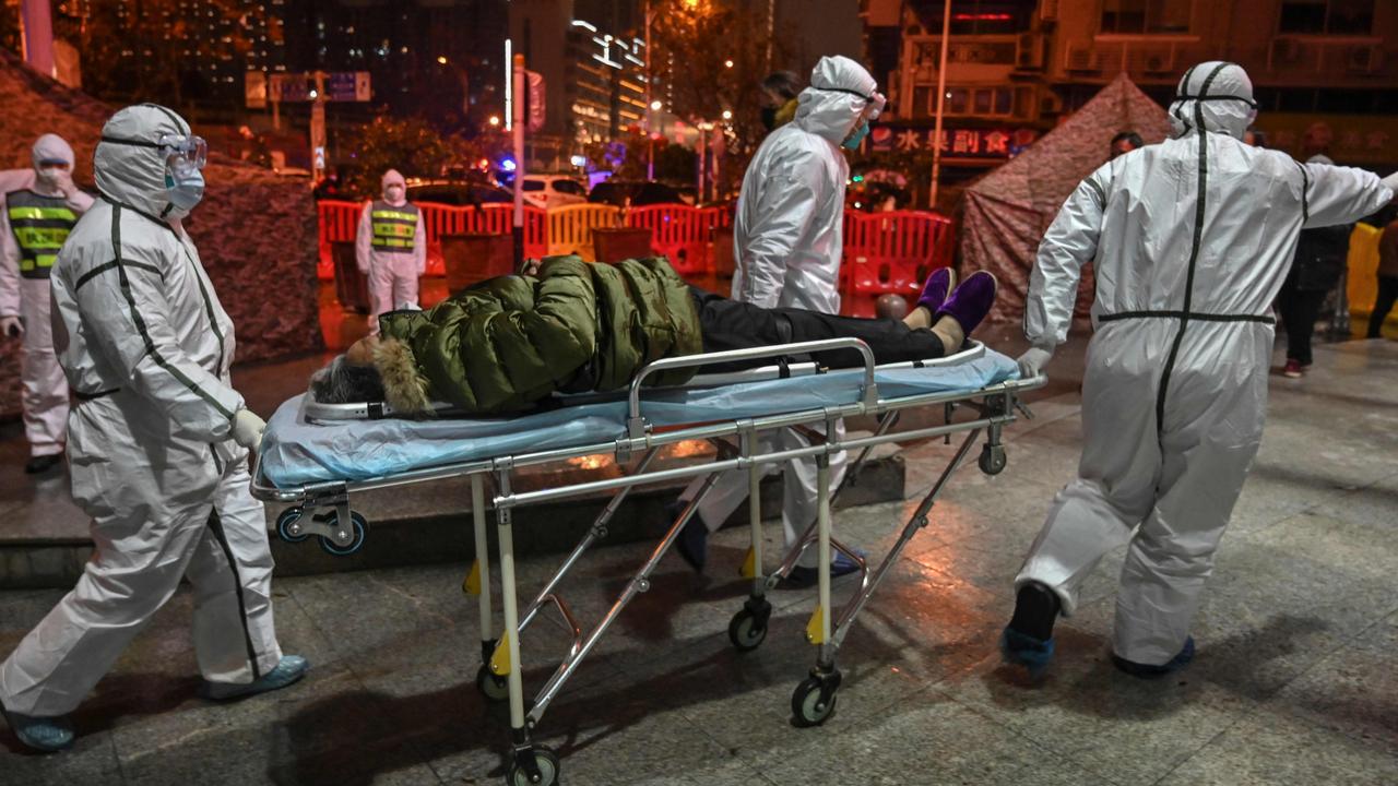 Chaos and cover-ups … medical staff in protective clothing arrive with a patient at the Wuhan Red Cross Hospital on January 25, 2020. At first some doctors were told to avoid masks.