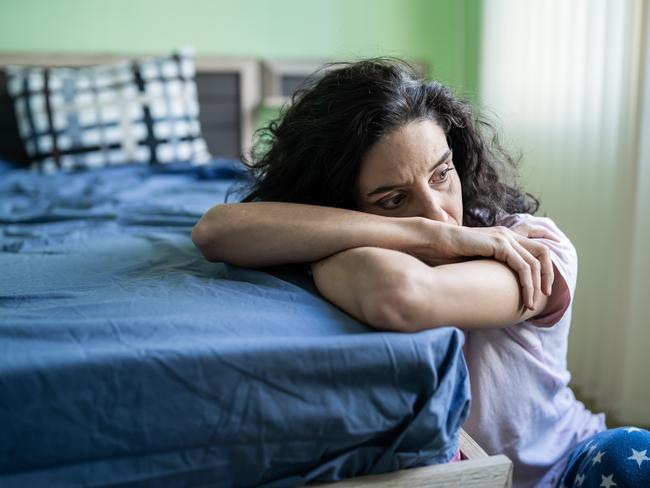 Mid adult woman sitting home alone, worried.