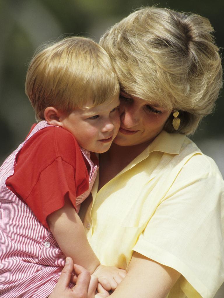 <b>1987:</b> Prince Harry shares a loving cuddle with Princess Diana during a holiday in Majorca, Spain. His relationship with his mother would be one of the defining loves of Harry’s life. Picture: Georges De Keerle/Getty