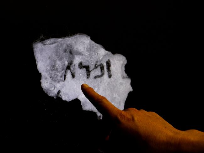 An Israel Antiquities Authority (IAA) staff member points at an infra-red scan of a fragment of a Dead Sea Scroll containing a previously unseen hidden text that was revealed with the aid of advanced imaging equipment, at the IAA's Dead Sea scrolls conservation laboratory in Jerusalem on May 2, 2018. The Dead Sea Scrolls are a collection of hundreds of biblical texts in Hebrew, Aramaic, and Greek discovered 45 years ago in the Qumran Caves near the Dead Sea. / AFP PHOTO / GALI TIBBON