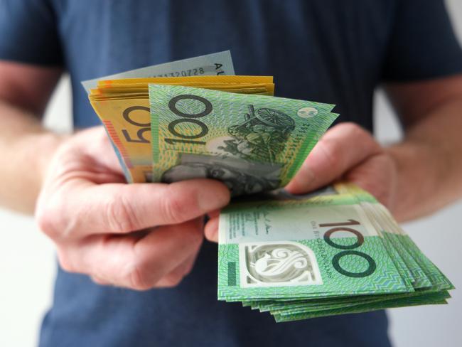 A man counting Australian dollar bills. A picture that describes buying, paying, handing out money, or showing money. Australian cash money generic