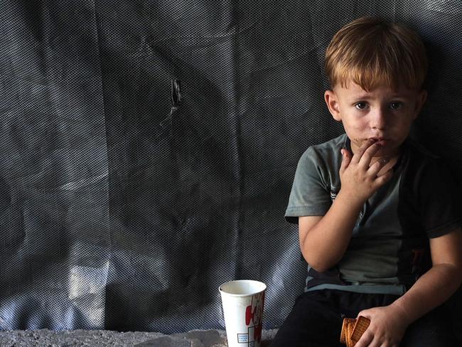 A child sits holding his biscuits at the Jabalia camp for displaced Palestinians in northern Gaza on August 29, 2024, amid the ongoing conflict between Israel and the militant Hamas group. (Photo by Omar AL-QATTAA / AFP)