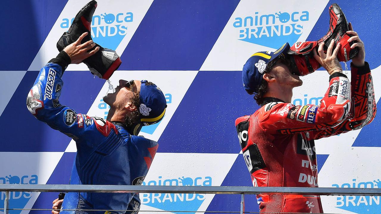 Suzuki Ecstar's Spanish rider Alex Rins (L) and third placed Ducati Lenovo's Italian rider Francesco Bagnaia drink from their driving boots on the podium.-