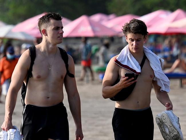 Foreign tourists walk on a beach in Seminyak, Badung regency on Indonesia resort island of Bali, on December 7, 2022. (Photo by SONNY TUMBELAKA / AFP)