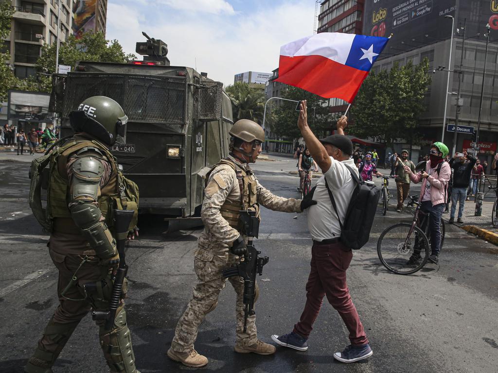 Army soldiers stop a man protesting with a Chilean flag, after a night of riots that forced Chile’s president Sebastian Pinera to announce a state of emergency. Picture: AP Photo