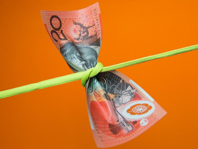 Australian twenty dollar note tied in a knot on a plain background, money generic squeeze pressure