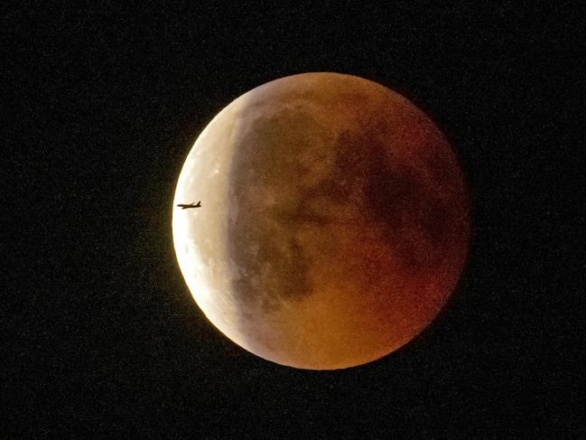 An airplane passes the blood moon immediately after the total lunar eclipse in Erfurt, Germany. Picture: AFP