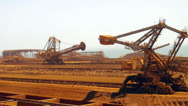 (FILES) This file photo taken on March 4, 2010 shows remote-controlled stackers and reclaimers moving iron ore to rail cars at Rio Tinto's Port Dampier operations in Western Australia's Pilbara region. - Rio Tinto's CEO and two other top officers resigned on September 11, 2020 after an uproar over the mining giant's destruction of an ancient Aboriginal heritage site to expand an iron ore mine in Australia. (Photo by Amy COOPES / AFP)