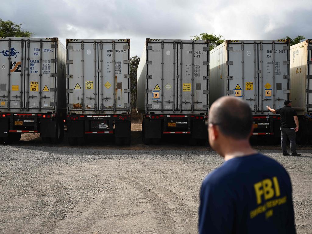 An FBI Evidence Response Team (ERT) agent watches as two additional refrigerated storage containers arrive adjacent to the Maui Police Forensic Facility where human remains are stored. Picture: AFP