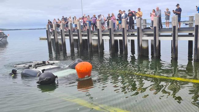 The crowd watches over the Rhyll boat ramp as the submerged Toyota HiLux is pulled out of the water. Picture: Supplied/Kate Crumpet