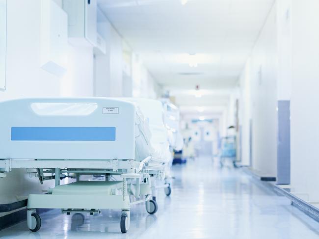 Shot of a hospital bed in an empty corridor of a modern hospital. Photo: iStock