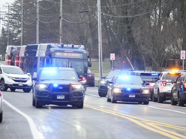 A bus carrying students leaves past emergency vehicles parked outside the Abundant Life Christian School. Picture: AP