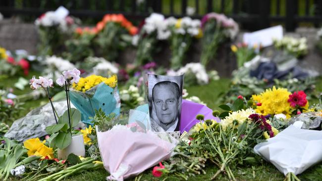 A photograph of Prince Philip, Duke of Edinburgh is positioned among floral tributes outside Windsor Castle. Picture: AFP