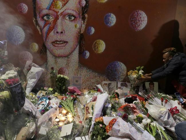 Grief ... Fans gathered to lay floral tributes to the singer near a mural by Australian street artist Jimmy C, in Brixton, South London. Picture: AP Photo/Tim Ireland