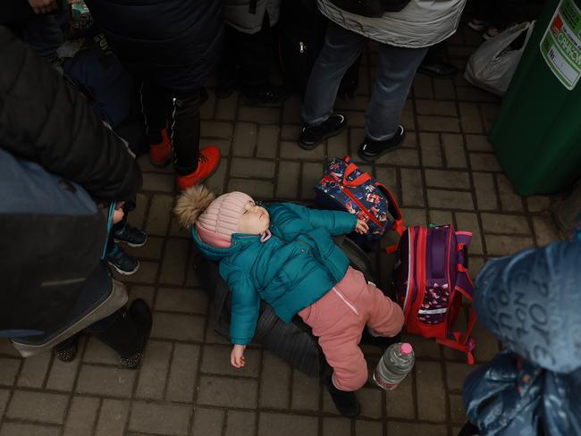 One-year-old Sophia lies on a piece of luggage as she and her mother wait for the train to Poland at the main train station in Lviv, Ukraine. Picture: Getty Images