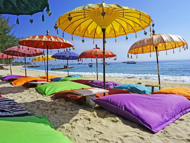 This image shows some colourful beach umbrellas and sand pillows in a pristine tropical beach bathed by the Bali sea.Escape 2 June 2024Kendall HillPhoto - iStock