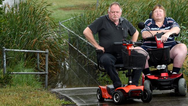 Russell Poulton (left) and Laurence Hubbard can’t get their scooters across this flooded Craigieburn bridge. Picture: Kylie Else