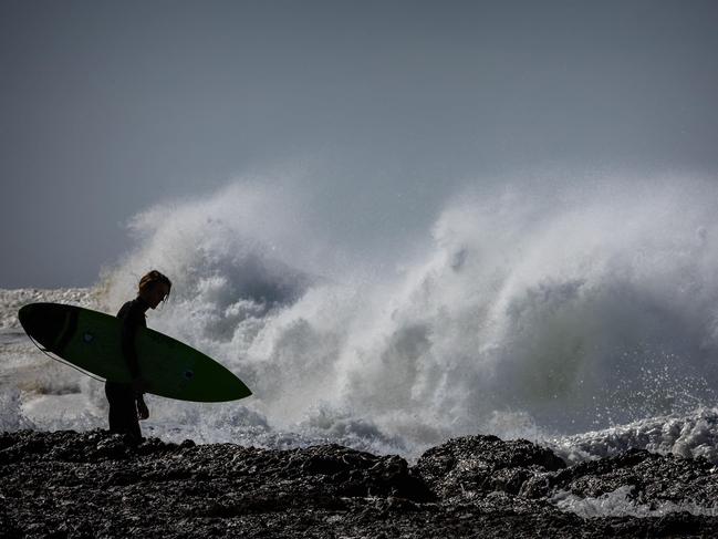 A Surfer prepares to take advantage of large swells as a result of wild weather at Snapper Rocks on the Gold Coast on July 23, 2022. (Photo by Patrick HAMILTON / AFP)