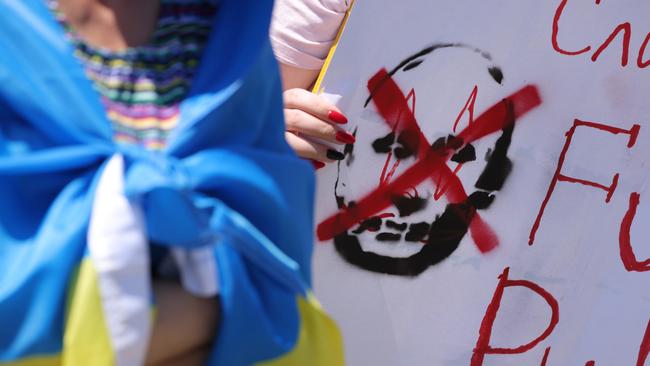 A German protester holds a sign denigrating Russian President Vladimir Putin during a rally in Berlin. Picture: Getty Images.