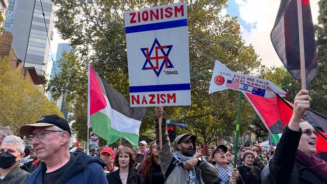 At a pro-Palestine rally held in Melbourne in May a man holds a placard conflating the star of David with a Swastika.