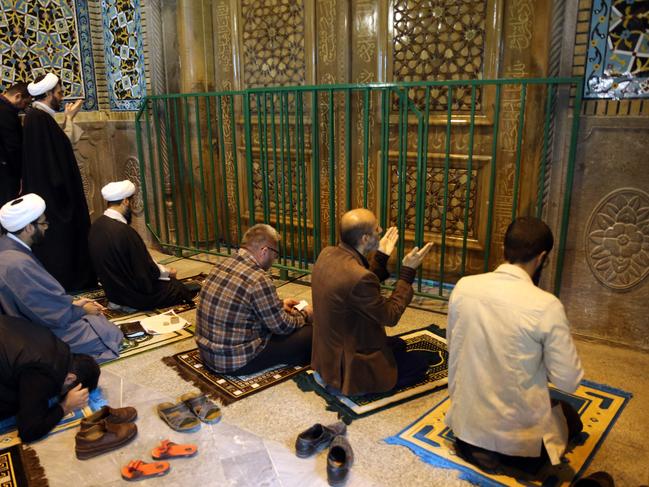 Iranians pray behind the closed doors of the Fatima Masumeh shrine in Iran's holy city of Qom. Picture: AFP