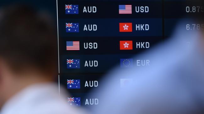 Pedestrians pass by currency prices on display at a bank on a street in Sydney on October 7, 2014. The Australian dollar hit a four-year-low of 86.43 US cents in New York last week as Australia's economy struggles to transition away from resources-led growth following an unprecedented boom in mining investment that is expected to fall-off sharply over the next year. AFP PHOTO/Peter PARKS