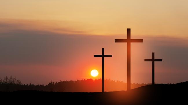 Christian cross on hill outdoors at sunrise.