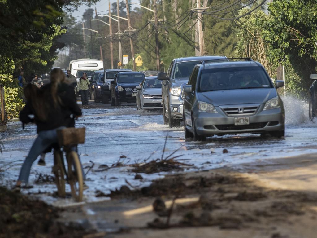 In this 2019 photo, vehicles pass through surf that washed over a roadway on Oahu's north shore in flooding from rising sea levels caused by global warming. Picture: AP