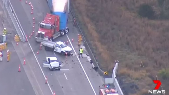 A large truck is directed around the wreckage of a car and a ute which collided head-on at Warnervale on the M1. Picture: 7 News