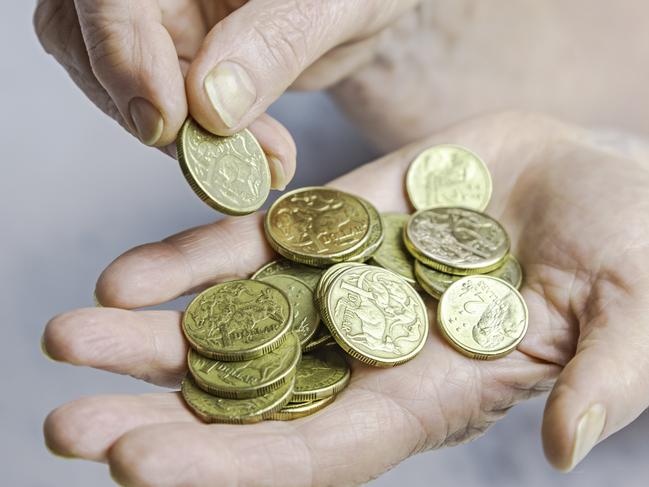 Close-up of senior female hands counting one and two dollar coins in hand.  Generic donations, giving money