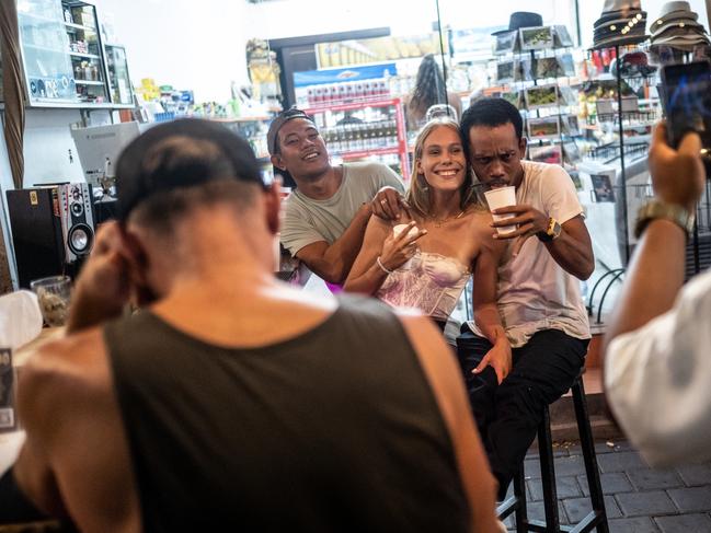 A foreign tourist woman smiles as she take a photograph with a local at a street bar in Bali, Indonesia. Picture: Getty Images