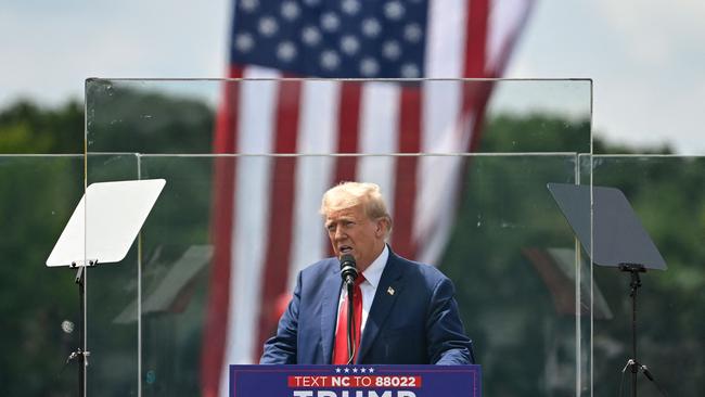 Former US President and Republican presidential candidate Donald Trump speaks behind bulletproof glass during a campaign rally at the North Carolina Aviation Museum &amp; Hall of Fame in Asheboro, North Carolina.