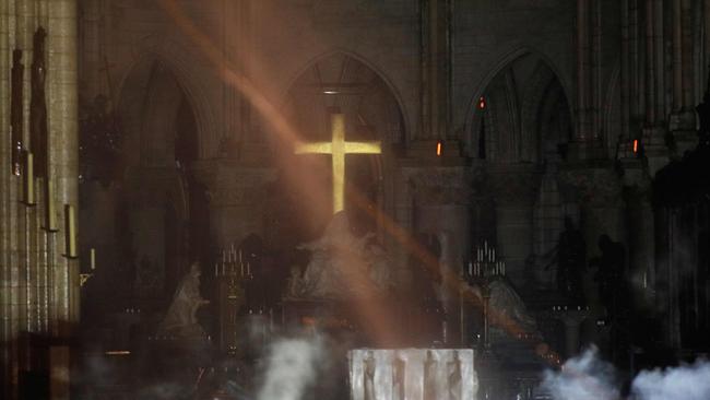 Smoke rises around the alter in front of the cross inside the Notre-Dame Cathedral. Picture: AFP