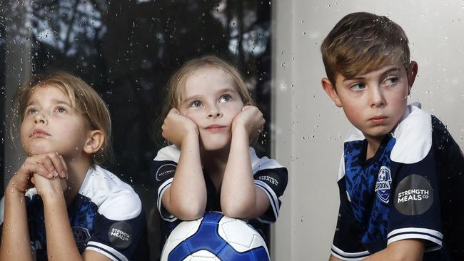 Romy Chamberlin, 7, Adelaide Stone, 7, and Hugo Stone, 11, in Pymble on Friday. They play for Gordon Football Club but have been frustrated by the number of times the council have closed the fields due to all the weekend rain. Picture: Richard Dobson