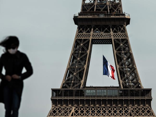 (FILES) In this file photo taken on May 11, 2020 a woman wearing a face mask walks as a French national flag flies on the Eiffel Tower in background in Paris on the first day of France's easing of lockdown measures in place for 55 days to curb the spread of the COVID-19 pandemic, caused by the novel coronavirus. - France's prime minister announced on August 27, 2020 that face masks become compulsory throughout Paris as he detailed a national trend of expanding coronavirus infections. (Photo by PHILIPPE LOPEZ / AFP)