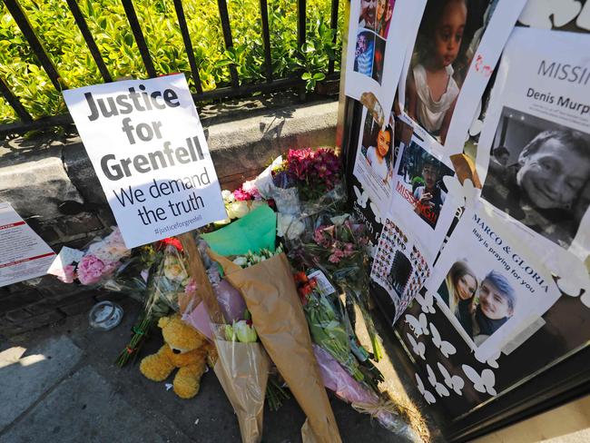 Flowers are pictured by a telephone box, covered with images of missing people, in Kensington, west London. Picture: AFP