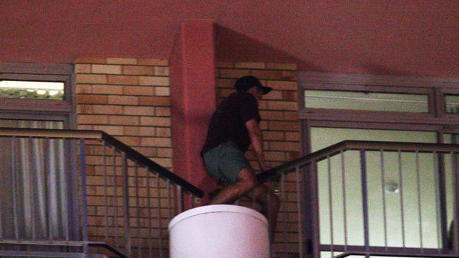 A schoolie climbs from one balcony to another.