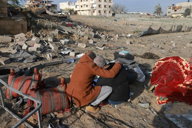 A Palestinian man comforts another as they inspect destruction in Rafah, southern Gaza, following Israeli air strikes